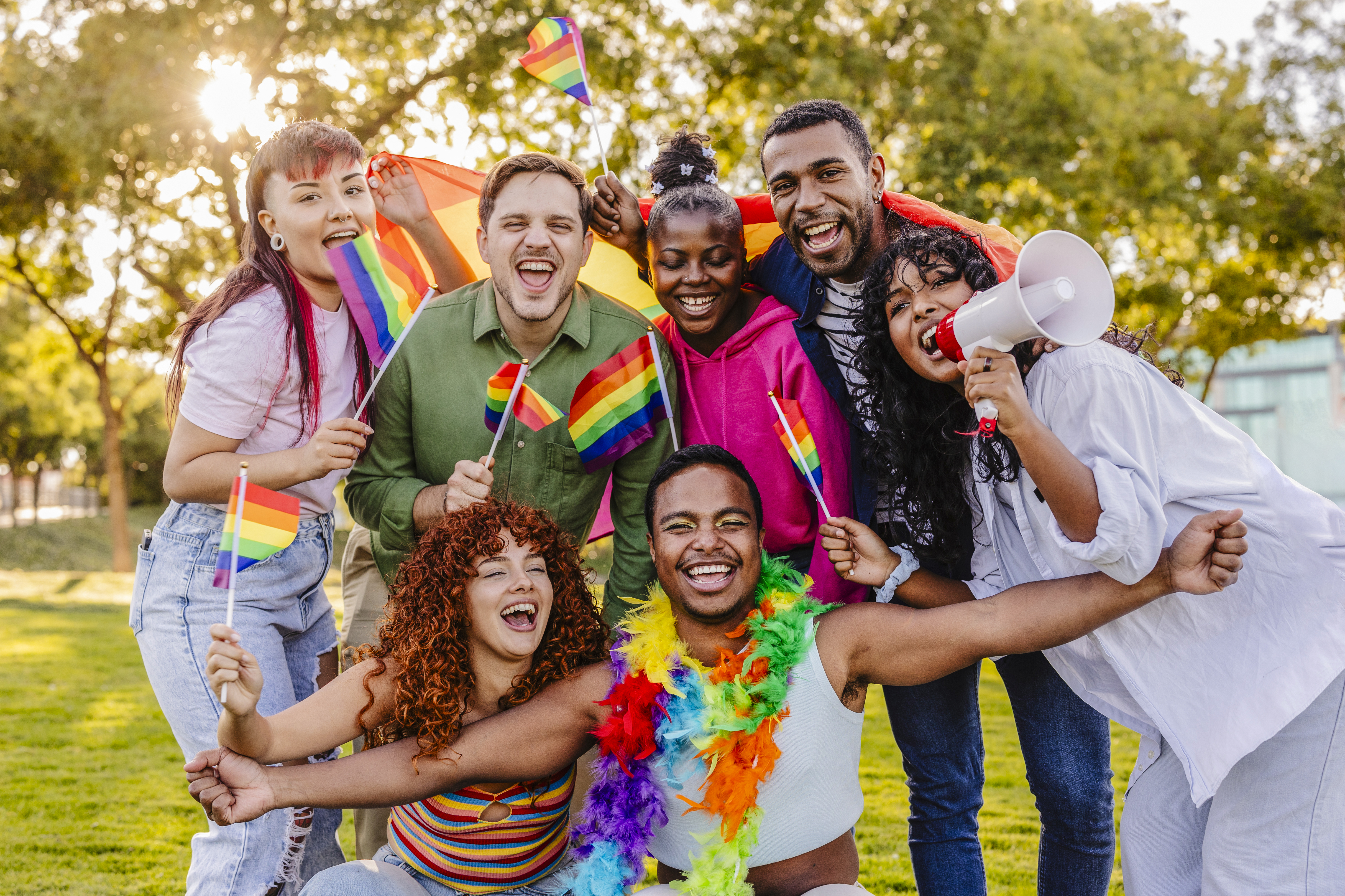 Friends celebrating Pride together outdoors with rainbow flags